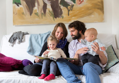 Young family reading storybook together on sofa