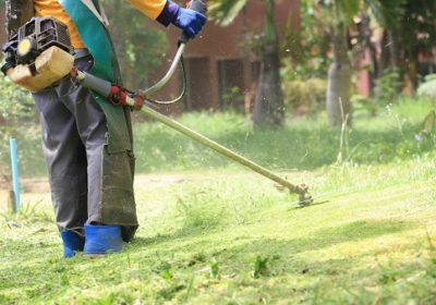 lawn mower worker cutting grass in green field.